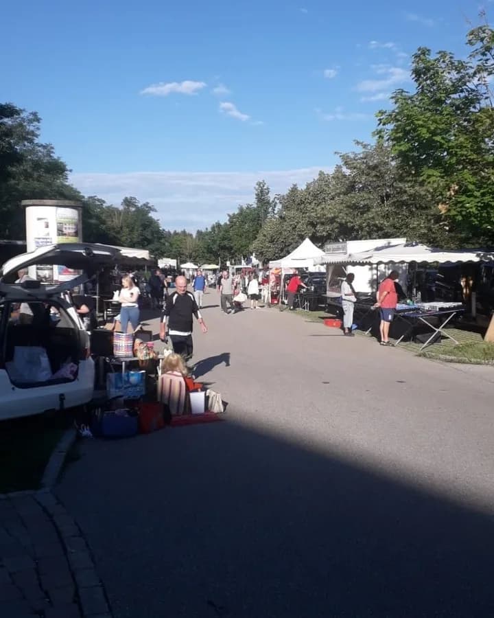 Händler packt am Markttag seine Ware aus dem Kofferraum, Stände im Hintergrund