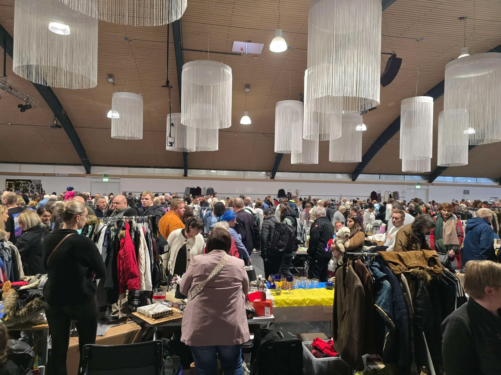 Volle Halle beim Flohmarkt von SR-Märkte: Besucher zwischen Kleiderständen und Tischen